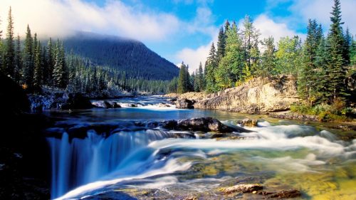 River and Waterfall in Green Forest and Mountains