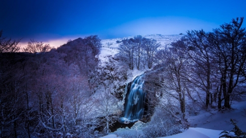 Wonderful waterfall in winter forest